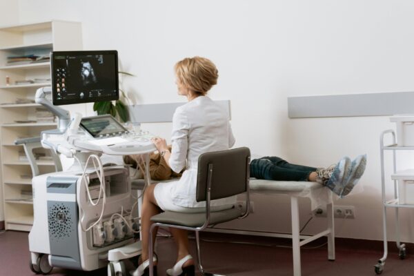 The Role of New Century Health in Modern Healthcare Medical professional performing an ultrasound examination on a patient in a clean, modern clinic, showcasing New Century Health technology and patient care